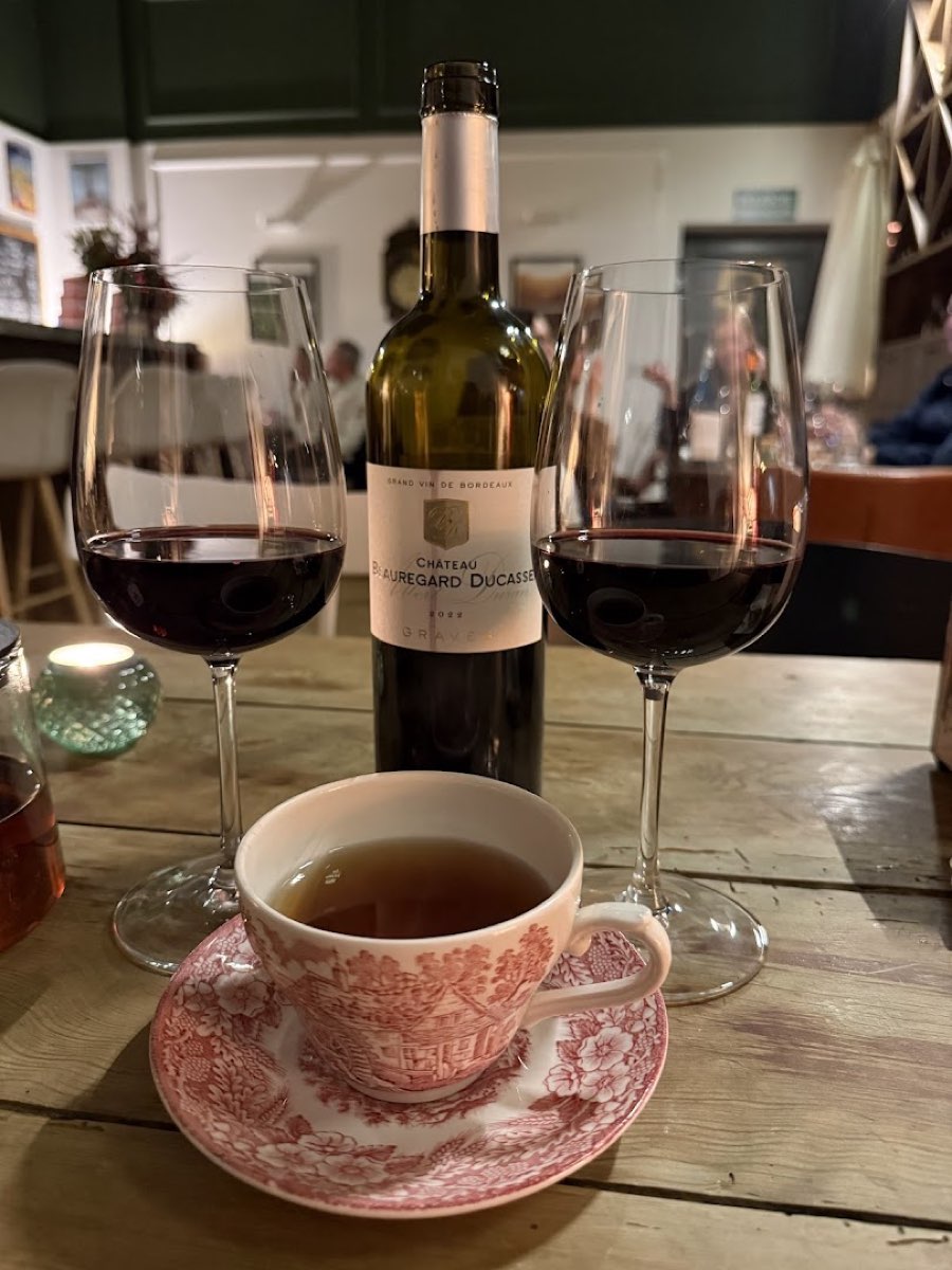 Butelka Bordeaux Château Beauregard Ducasse Graves, dwa kieliszki czerwonego wina i vintage'owa filiżanka