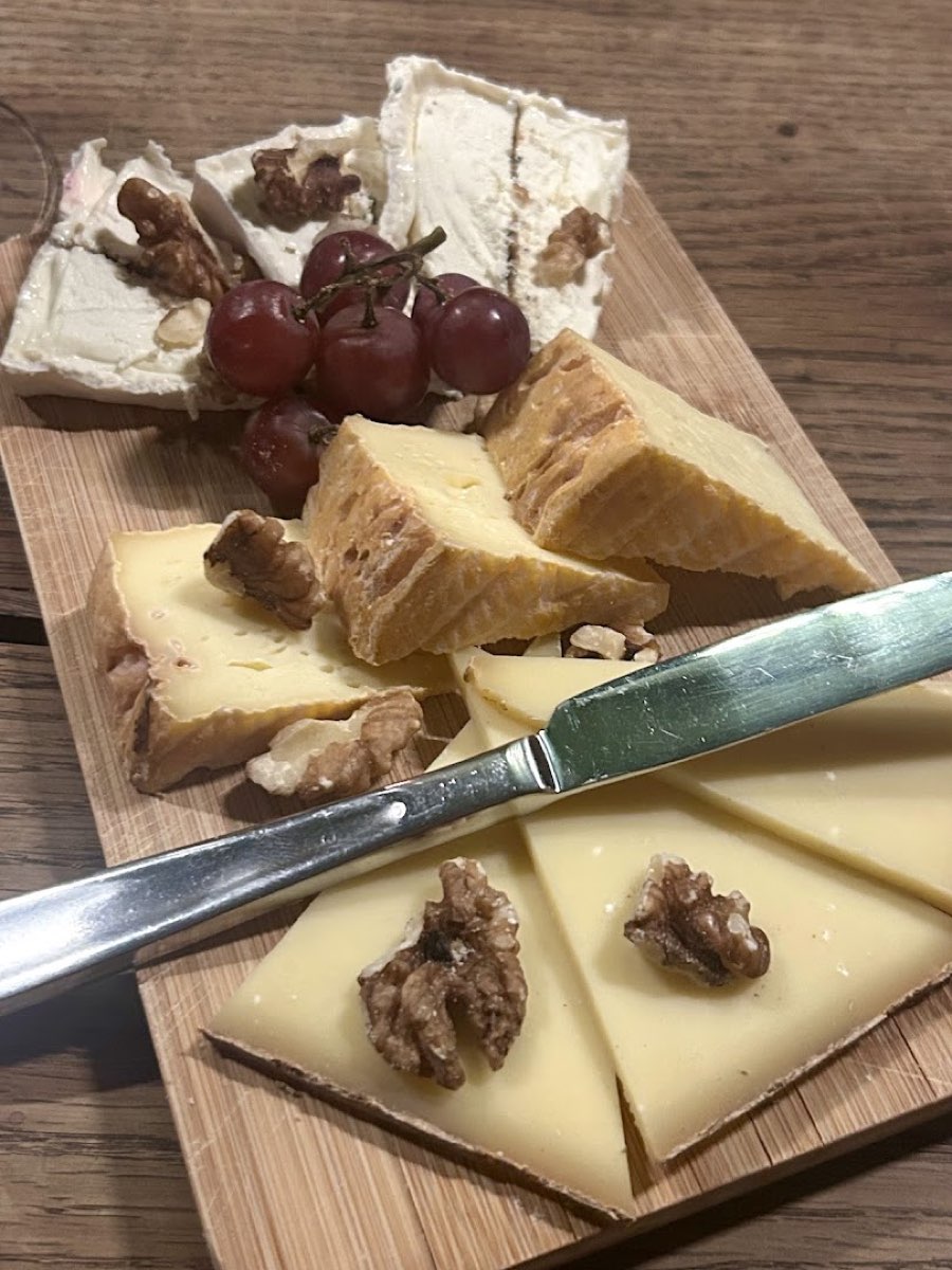 Pieczywo i deska wędlin z nożem, podane na drewnianym stole